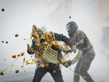 Seorang pria melemparkan telur ke arah lawannya saat Festival Els Enfarinats di kota Ibi, Spanyol, Rabu (28/12). Els Enfarinats adalah festival tradisional Spanyol yang telah berusia sekitar 200 tahun. (AFP PHOTO / Jamie Reina)