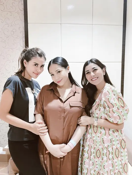 Syahnaz berpose menggandeng Gigi sebelum ia melahirkan anak keduanya Rayyanza. Syahnaz tampil sederhana dengan kaus hitam bermotif dan celana panjang hitam, Gigi dengan piyama daster cokelat, dan Nisya tampil manis dengan dress bermotif floral. Foto: Instagram.