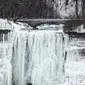 Dua orang turis berjalan di depan Air Terjun Niagara, Ontario, Kanada, Senin (9/1). Amerika utara dan Kanada kini sedang terjadi penurunan temperatur sehingga membuat wilayah tersebut terkena cuaca dingin ekstrem. (Geoff Robins/AFP)