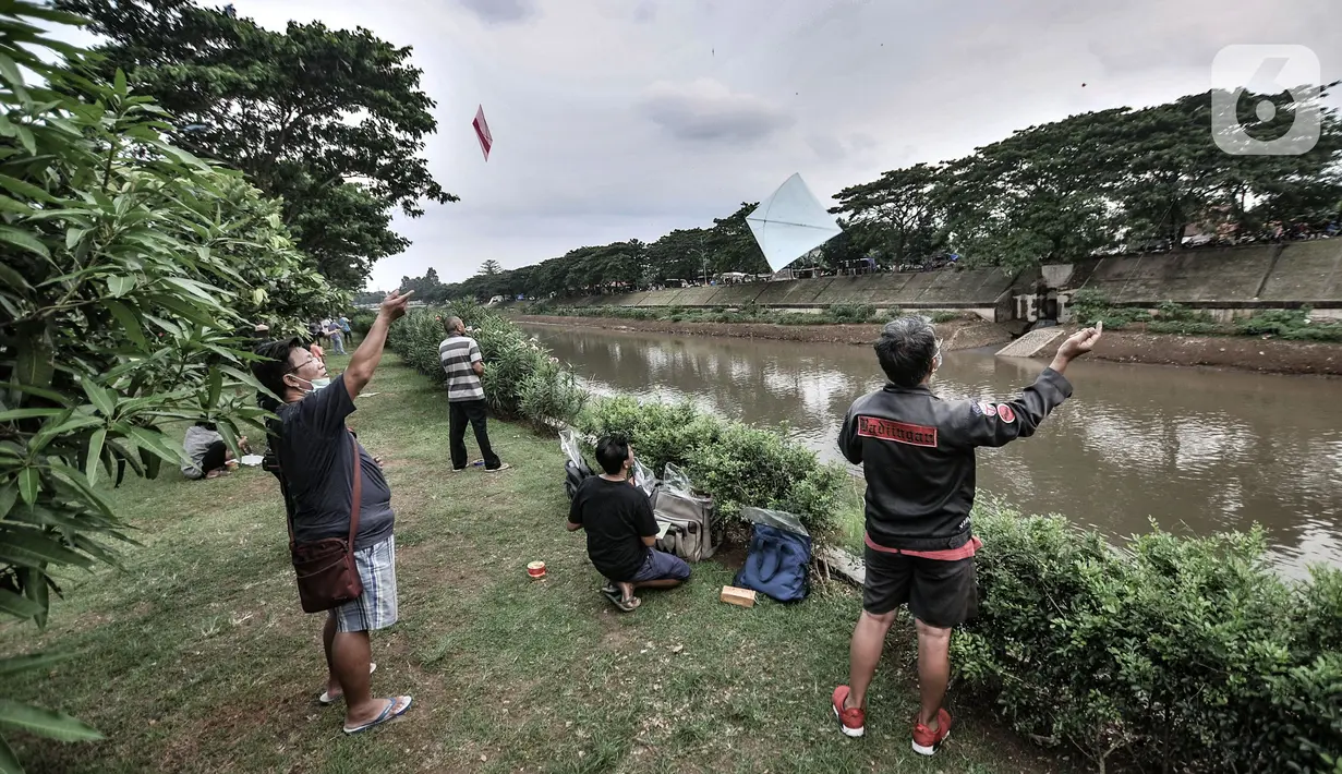 Warga bermain layang-layang di pinggir Kanal Banjir Timur (KBT), Duren Sawit, Jakarta, Senin (19/4/2021). KBT menjadi lokasi favorit warga untuk mengisi waktu menunggu buka puasa atau ngabuburit, salah satunya dengan bermain layang-layang bersama keluarga. (merdeka.com/Iqbal S Nugroho)