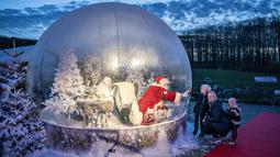 Seseorang yang berpakaian seperti Sinterklas terlihat dalam bola salju seukuran aslinya saat membuka musim Natal di Kebun Binatang Aalborg, di tengah krisis virus corona yang berlanjut, di Aalborg, Denmark pada Jumat (13/11/2020). (Henning Bagger / Ritzau Scanpix / AFP)