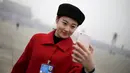 Seorang wanita selfie saat Kongres Rakyat Nasional China di Beijing, Sabtu (5/3/2016). Para wanita cantik ini hadir untuk menyambut para tamu delegasi NPC. (Reuters/Damir Sagolj)