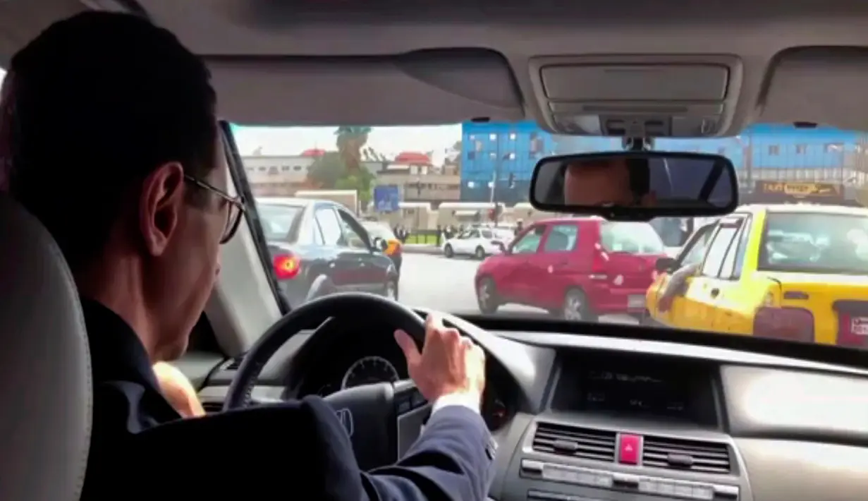 Presiden Suriah Bashar al-Assad mengemudikan mobilnya untuk mengunjungi pasukan garis depan di Ghouta timur, Suriah, Minggu (18/3). Mobil Honda Civic  yang dikemudikannya itu dibawa dari Damaskus ke Ghouta Timur. (Syrian Presidency Facebook Page/AP)
