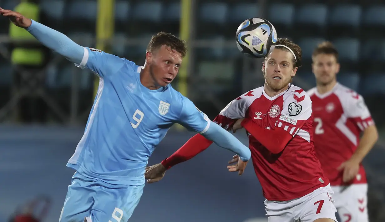 Gelandang Denmark Mathias Jensen berebut bola dengan penyerang Nicola Nanni dalam matchday kedelapan  Kualifikasi Euro 2024 Grup H di Stadion San Marino di Serravalle, Rabu (18/10/2023) dini hari WIB. (AP Photo/Felice Calabro)