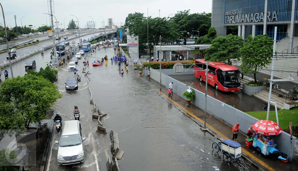 Genangan air telihat di Jalan S Parman, tepat di depan Universitas Tarumanagara (Untar), Jakarta, Selasa (21/2). Lantaran akses masuk menuju kampus tergenang air, pihak Kampus hari ini memutuskan untuk meliburkan perkuliahan. (Liputan6.com/Gempur M Surya)
