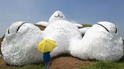Salah satu pengunjung berdiri di depan kelinci raksasa yang dirancang oleh seniman Belanda Florentijn Hofman dan dipamerkan pada Taoyuan Land Art Festival di Taiwan, (3/9/2014). (REUTERS/Pichi Chuang)