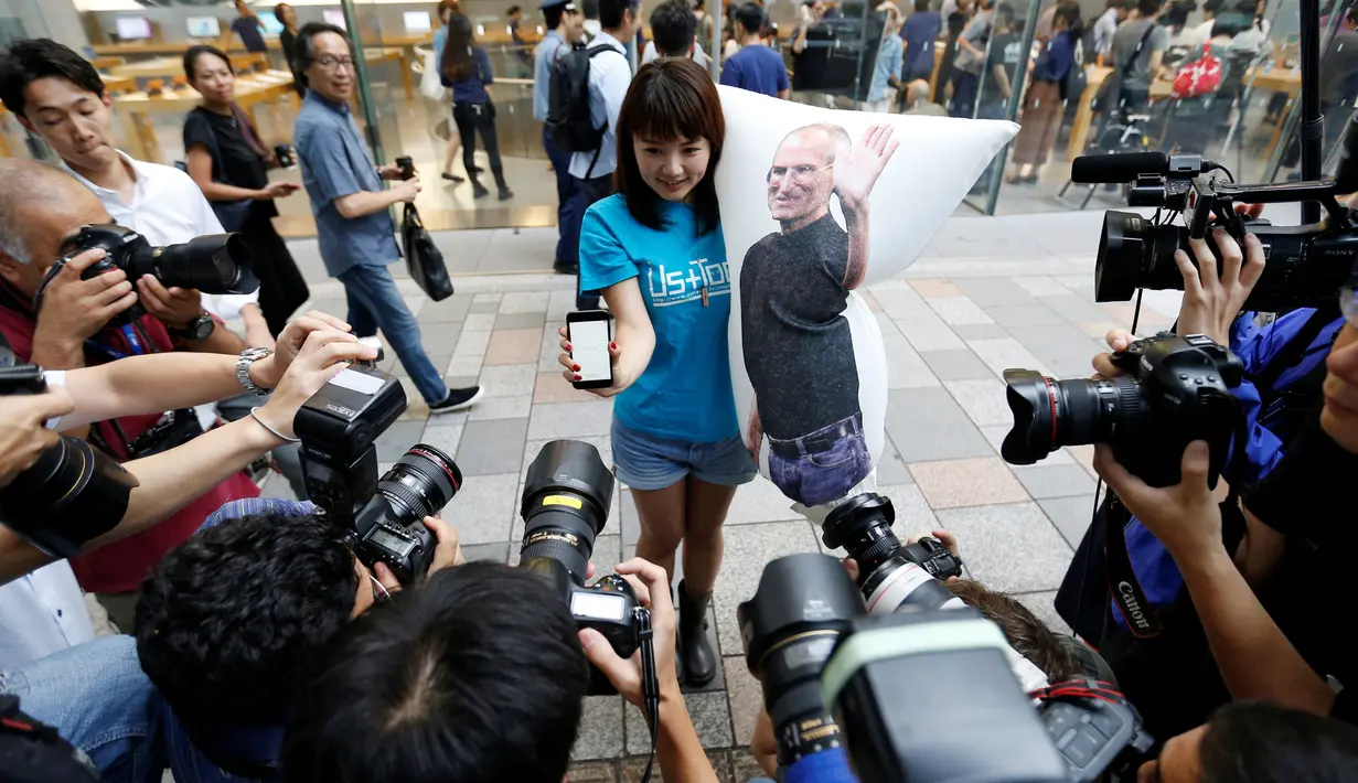 Ayano Tominaga pose dengan iPhone 7 sambil membawa bantal di Tokyo, Jepang, Jumat (16/9). Pembeli iPhone7 hari ini menjadi bagian dari pembeli pertama di seluruh dunia. (REUTERS / Issei Kato)