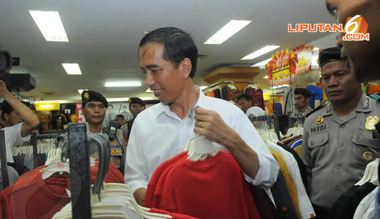 Dengan pengawalan dari petugas polisi, Jokowi tampak memilih beberapa helai kaos (Liputan6.com/Herman Zakharia) 
