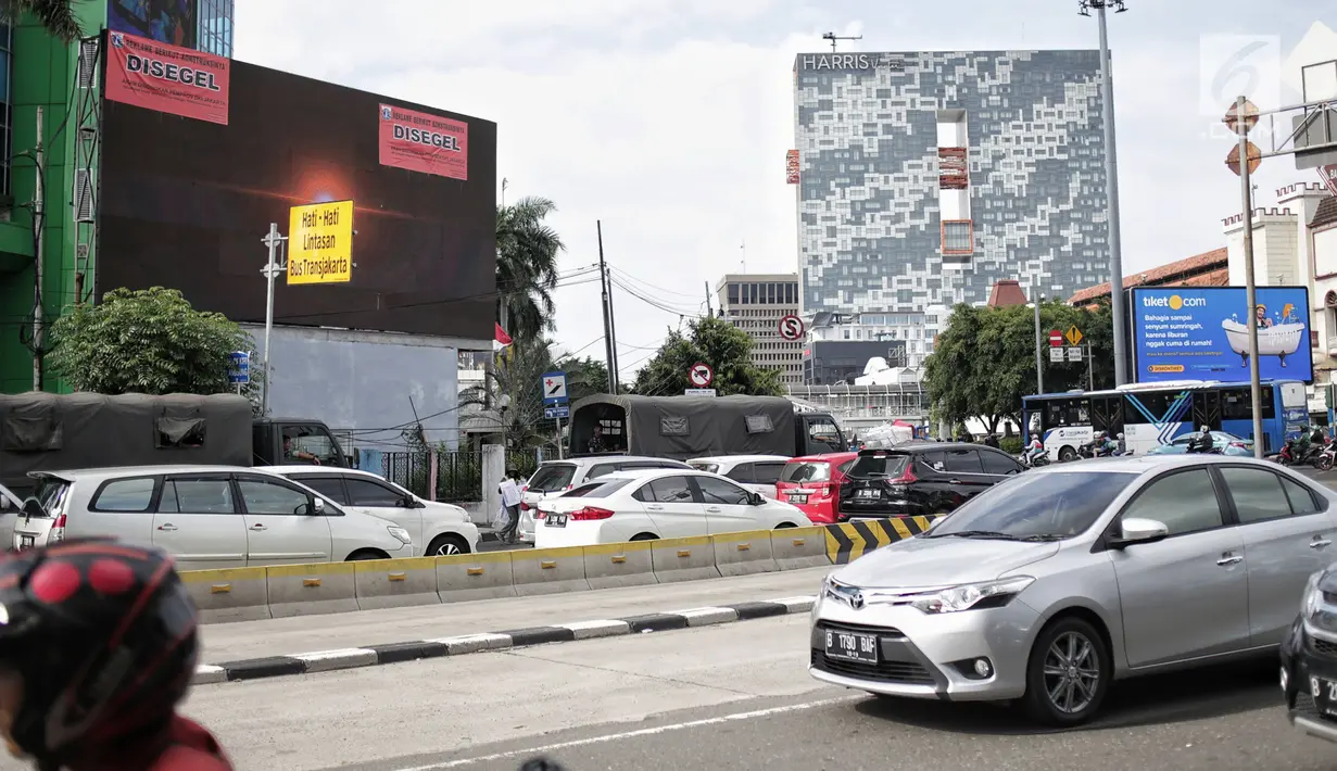 Kendaraan melintas di dekat Layar reklame yang disegel di kawasan perempatan Harmoni, Jakarta, Selasa (29/1). Reklame yang disegel seluruhnya berlokasi di kawasan kendali ketat. (Liputan6.com/Faizal Fanani)
