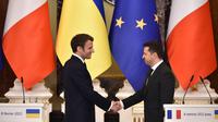 Presiden Ukraina Volodymyr Zelensky (kanan) dan Presiden Prancis Emmanuel Macron berjabat tangan usai konferensi pers setelah pertemuan di Kyiv, Ukraina, 8 Februari 2022. Volodymyr Zelensky berharap segera mengadakan pertemuan puncak dengan pemimpin Rusia, Prancis, dan Jerman. (Sergei SUPINSKY/AFP)