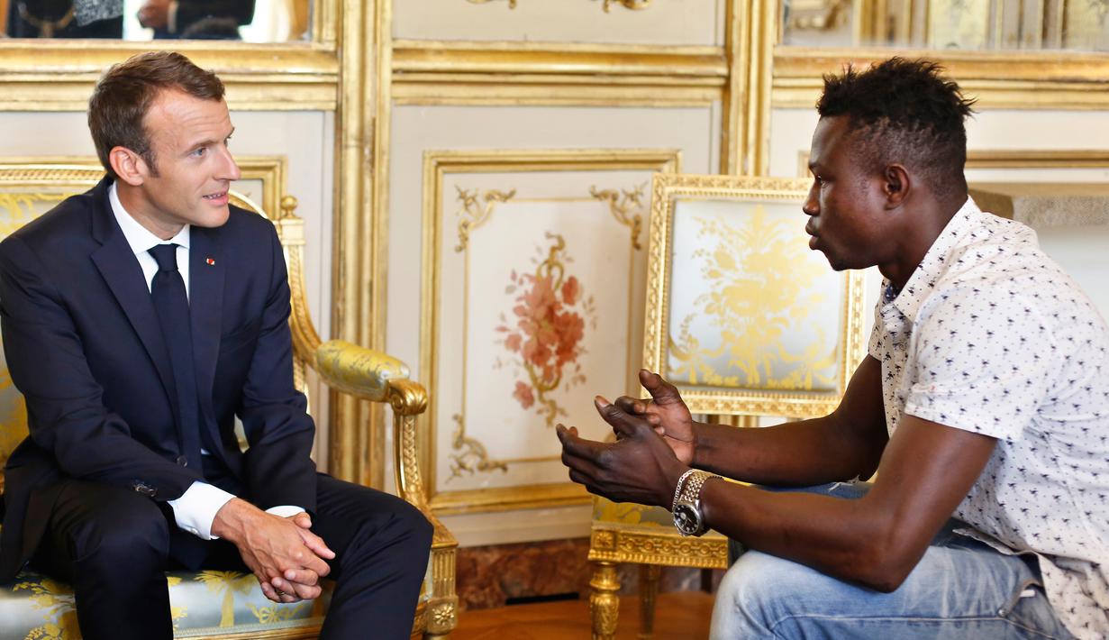 Presiden Prancis Emmanuel Macron (kiri) berbincang dengan Mamoudou Gassama di Istana Elysee, Paris, Prancis, Senin (29/5). Berkat kepahlawanannya, Macron menghadiahinya medali dan menawarinya kewarganegaraan Prancis. (AP Photo/Thibault Camus, Pool)
