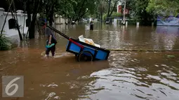 Warga melintasi banjir yang menggenangi Kommplek Perumahan yang Banjir di Hang Lekiu, Kebayoran Baru, Jakarta, Jumat (11/11). Hujan deras disertai angin yang mengguyur wilayah Jakarta, mengakibatkan daerah ini banjir. (Liputan6.com/Johan Tallo)