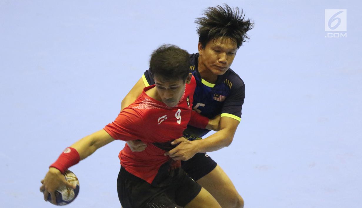 Pemain bola tangan Indonesia, Rufan Pujianto (depan) mencoba lolos dari kawalan pemain Malaysia pada penyisihan grup 3 bola tangan Asian Games 2018 di GOR PP POPKI, Jakarta, Minggu (26/8). Indonesia unggul 31-22. (Liputan6.com/Helmi Fithriansyah)