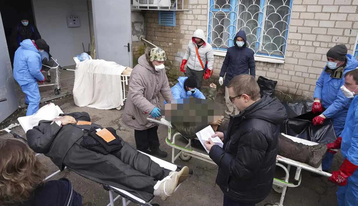 Jenazah disiapkan sebelum dimasukkan ke dalam kantong jenazah dan dimakamkan pada kuburan massal di pinggiran Mariupol, Ukraina, 9 Maret 2022. (AP Photo/Evgeniy Maloletka)
