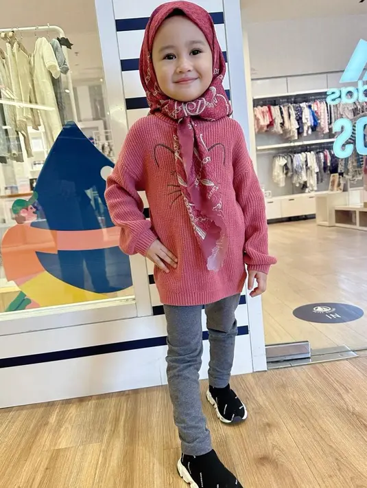 Khalisa juga bergaya kasual dengan mengenakan kerudung merah bermotif yang serasi dengan sweater bergambar. Dipadukan celana abu-abu dan sneakers hitam.  [@kartikaputriworld]