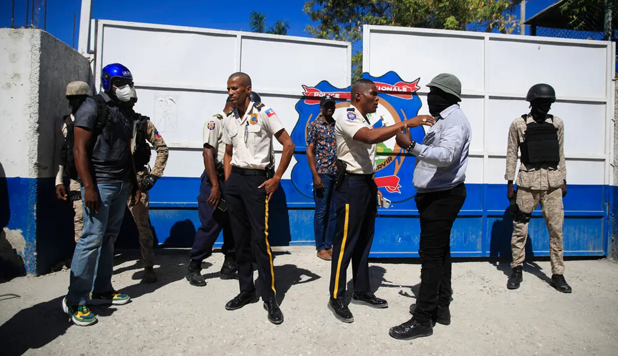 Seorang petugas polisi mencoba menenangkan petugas polisi lainnya yang mengenakan pakaian jalanan saat dia mencoba memasuki markas polisi saat protes untuk mengecam tata kelola polisi yang buruk di Port-au-Prince, Haiti, 26 Januari 2023. Lebih dari 100 demonstran dilaporkan memblokir jalan, membakar ban, merusak kamera pengawas keamanan, dan kendaraan. (AP Photo/Odelyn Joseph)