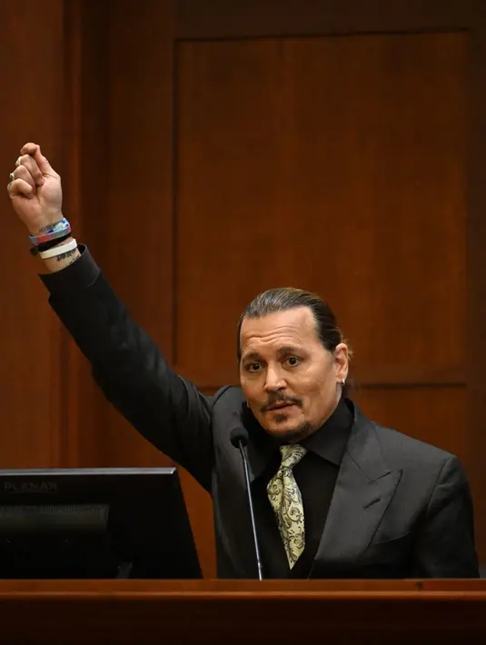 Aktor Johnny Depp bersaksi pada persidangan pencemaran nama baik di Fairfax County Circuit Courthouse, Fairfax, Virginia, Amerika Serikat, 19 April 2022. Amber Heard menyebut Johnny Depp sebagai “figur publik yang mewakili kekerasan dalam rumah tangga.” (JIM WATSON/POOL/AFP)