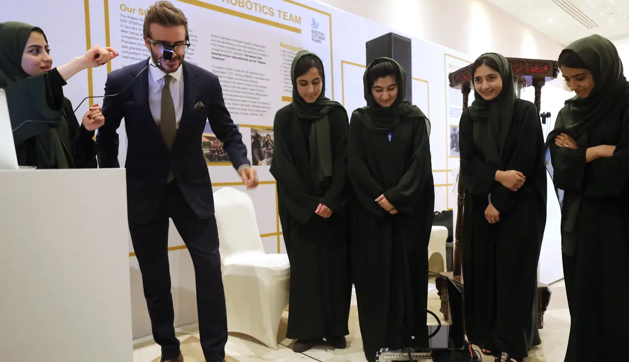 Mantan pemain sepak bola Inggris dan duta UNICEF, David Beckham bermain dengan robot yang dibuat oleh Tim Robotika Putri Afghanistan di Forum Doha di ibukota Qatar (27/3/2022). (Marwan Tahtah/Mofa/Doha Forum)