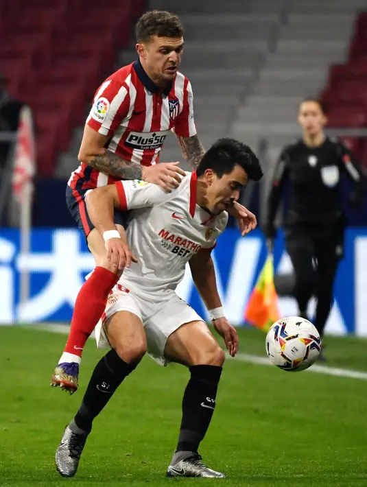 Bek Atletico Madrid, Kieran Trippier (kiri) melompati bek Sevilla, Marcos Acuna saat berebut bola dalam lanjutan Liga Spanyol 2020/2021  di Stadion Wanda Metropolitano, Madrid, Spanyol, Rabu (13/1/2021) dini hari WIB. Atletico Madrid membungkam Sevilla dengan skor 2-0. (PIERRE-PHILIPPE MARCOU/AFP)