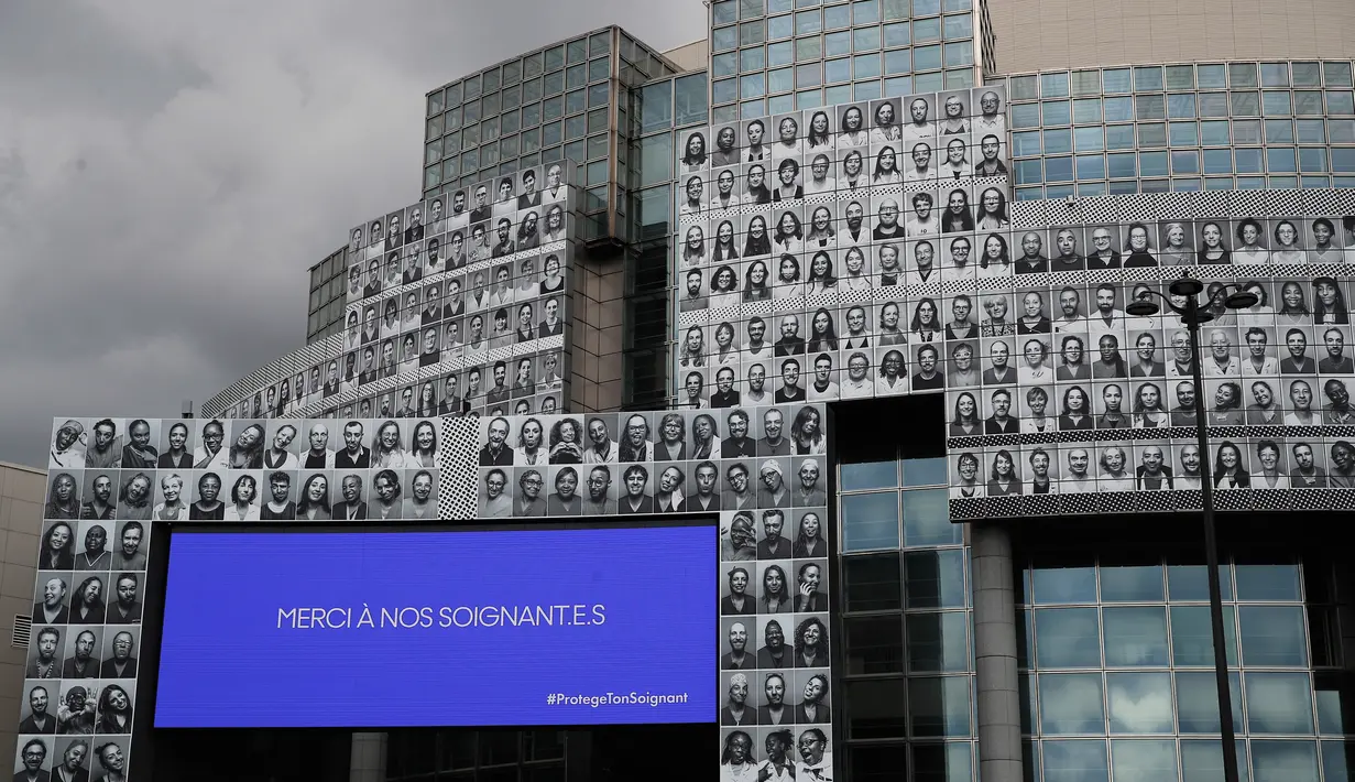 Potret para petugas kesehatan yang ditempelkan di bagian depan Bastille Opera di Paris, Prancis, Jumat (10/7/2020). Potret hitam putih untuk memberi penghormatan kepada pekerja medis Covid-19 itu merupakan kreasi seniman Prancis dan fotografer JR. (AP Photo/Francois Mori)