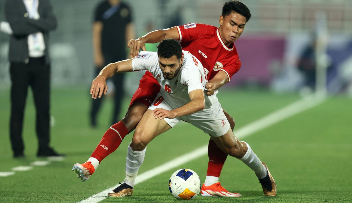 Pemain Timnas Indonesia U-23, Muhammad Ferarri (belakang) berebut bola dengan pemain Yordania U-23, Mohannad Abu Taha pada laga ketiga Grup A Piala Asia U-23 2024 di Abdullah bin Khalifa Stadium, Doha, Qatar, Minggu (21/4/2024). (AFP/Karim Jaafar)