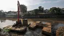 Alat berat melakukan pengerukan tumpukan sisa lumpur dan tanah yang menumpuk di pinggir kali Ciliwung, Jakarta, Kamis (28/7). Tumpukan tanah dan lumpur sisa dari pengerukan kali Ciliwung mulai dibersihkan.(Liputan6.com/Yoppy Renato)