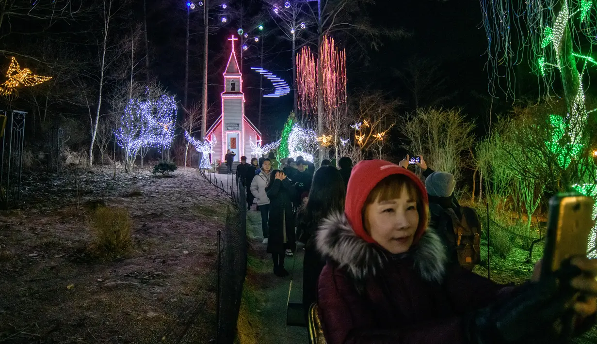 Gambar yang diambil 11 Januari 2020, pengunjung melihat tampilan beragam kerlip lampu di Garden of Morning Calm, sebelah timur Seoul di distrik Gapyeong, Korea Selatan. Festival cahaya tahunan tersebut dinikmati saat musim dingin, Desember sampai akhir bulan Maret. (Ed JONES / AFP)