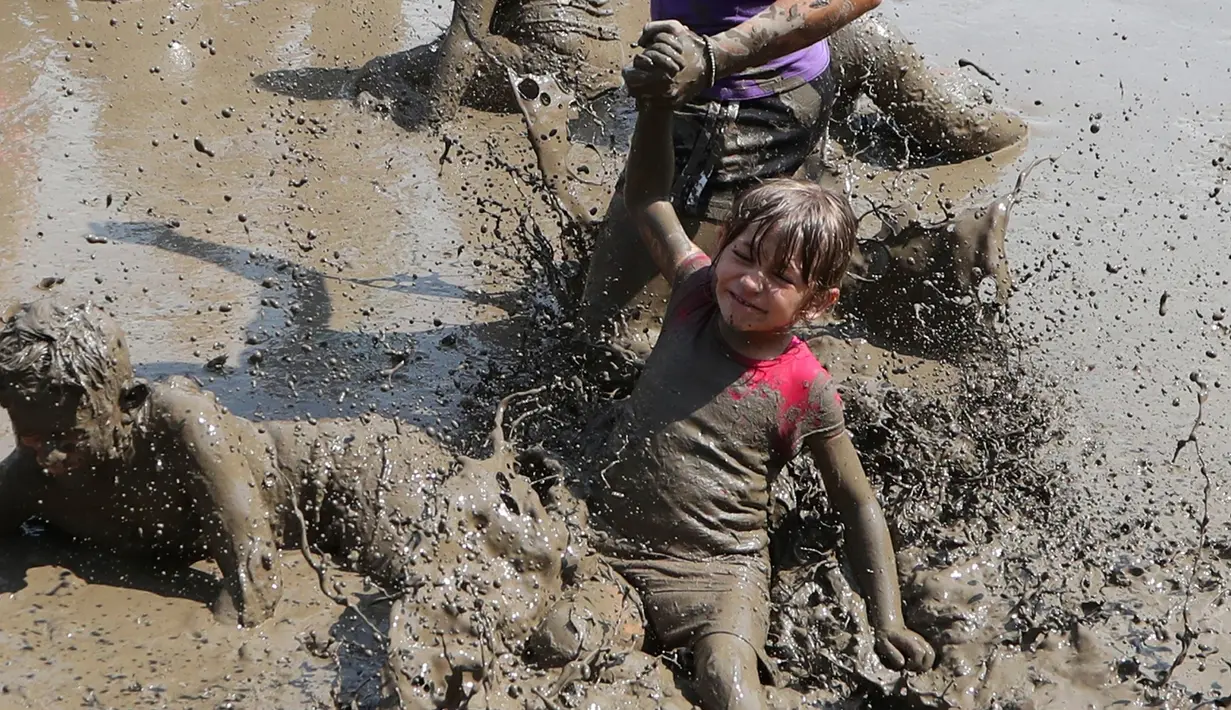 Emily Jamerson jatuh ke dalam kubangan berisi lumpur saat perayaan Mud Day atau Hari Lumpur Tahunan di Westland, Michigan, AS, Selasa (10/7). Dalam Mud Day kali ini para pesertanya yang ikut adalah anak-anak.  (AP/Carlos Osorio)