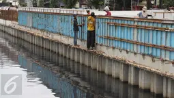 Para pekerja menyelesaikan pembangunan turap di sepanjang Kali Grogol, Jakarta, Senin (21/11). Pembangunan turap dilakukan untuk mencegah meluapnya air kali saat hujan dan ditargetkan selesai 20 Desember 2016. (Liputan6.com/Gempur M Surya)