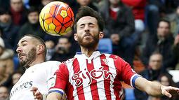 Striker Real Madrid, Karim Benzema, duel udara dengan pemain Sporting Gijon, Alez Menendez. Madrid terpaut empat poin dari Atletico yang berada di puncak klasemen. (Reuters/Andrea Comas)