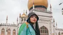 Denada tampil nyentrik dengan layering outfit warna-warni sambil berpose di masjid Sultan Arab, Singapura. [Foto: IG/denadaindonesia].