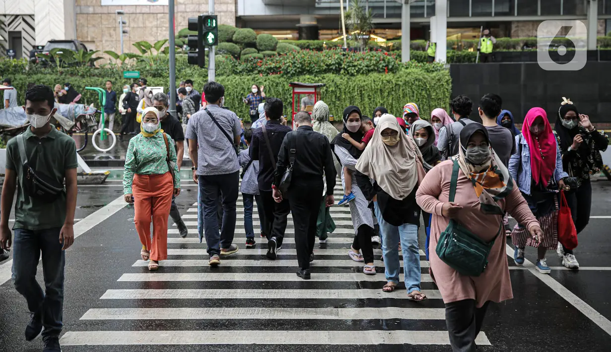 Warga menyeberang jalan di kawasan Jalan MH Thamrin, Jakarta, Rabu (28/12/2022). Walau sempat disebutkan ada potensi badai dahsyat yang melanda kawasan Jakarta–Bogor–Depok–Tangerang–Bekasi (Jabodetabek) pada hari ini, warga Jakarta terpantau masih banyak beraktivitas di luar ruangan. (Liputan6.com/Faizal Fanani)