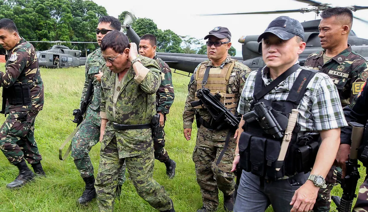 Presiden Filipina, Rodrigo Duterte mengunjungi markas militer lokal Marawi di Camp Ranao, Kamis (20/7). Dengan mengenakan pakaian samaran dan sepatu boots, Presiden Duterte datang bersama sejumlah menteri kabinet. (AP Photo)