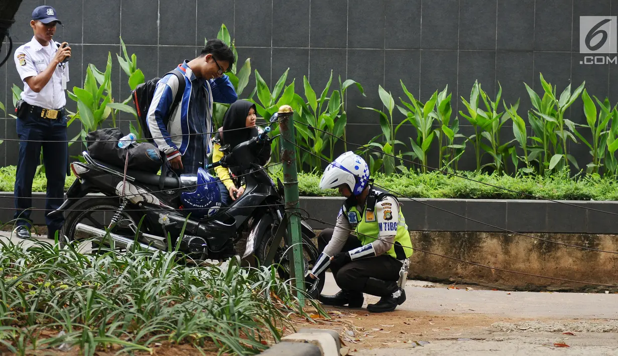 Petugas kepolisian menggembosi ban motor yang parkir di trotoar Jalan Kebon Sirih, Jakarta, Senin (17/7). Hal ini tindak lanjut maraknya pelanggaran lalu lintas di kawasan pedestrian Jalan Kebon Sirih. (Liputan6.com/Helmi Fithriansyah)