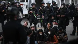 Petugas polisi berdiri di sekitar pengunjuk rasa yang ditangkap setelah demonstrasi menentang operasi imigrasi federal di dekat Balai Kota Los Angeles, Amerika Serikat pada 11 Juni 2025. (RONALDO SCHEMIDT/AFP)