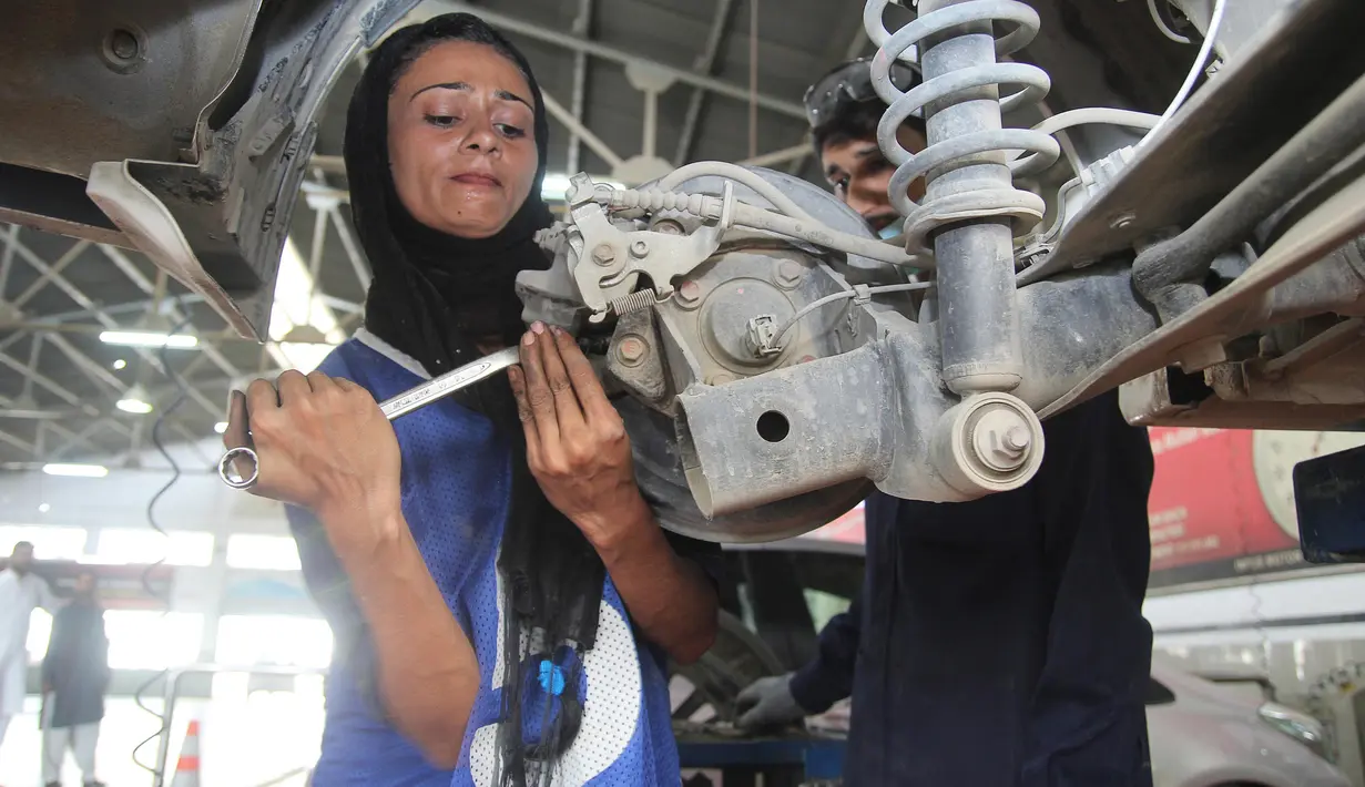 Montir perempuan Pakistan Uzma Nawaz (24) memperbaiki mobil di sebuah bengkel kota Multan, 1 September 2018. Sejak menjadi montir perempuan pertama di Pakistan yang konservatif, Uzma kerap menghadapi dua reaksi umum, terkejut dan syok. (S.S. Mirza/AFP)