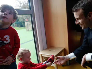 Presiden Prancis Emmanuel Macron bermain dengan anak-anak saat mengunjungi Graffiti's- Association Le Moulin Vert di Normandia, Prancis (5/4). Pada kunjungannya Presiden Emmanuel Macron berinteraksi dengan anak-anak autis. (AP / Christophe Ena, Pool)