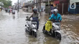 Pengendara motor mendorong kendaraannya melintasi genangan air ketika banjir merendam Jalan KH. Hasyim Ashari, Tangerang, Banten, Sabtu (16/7/2022). Hujan deras mengguyur sejak Jumat siang hingga Sabtu pagi. (Liputan6.com/Angga Yuniar)