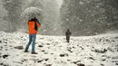 Turis India (kiri) mengambil foto selama hujan salju di Gulmarg, sekitar 55 km sebelah utara Srinagar, Kashmir, Selasa (3/1). Gelombang dingin yang melanda Kashmir kian parah hingga mencapai suhu di bawah nol derajat celcius. (Tauseef Mustafa/AFP)