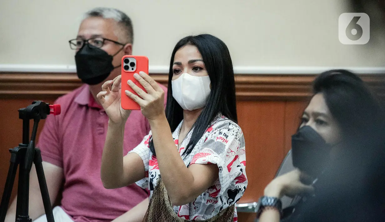 Aktris Nirina Zubir (tengah) mengambil gambar saat menghadiri sidang lanjutan kasus mafia tanah di Pengadilan Negeri Jakarta Barat, Jakarta, Selasa (7/6/2022). Nirina Zubir melaporkan mantan ART almarhumah ibunya, yang bernama Riri Khasmita pada November 2021. (Liputan6.com/Faizal Fanani)