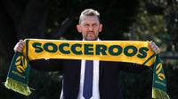 Tony Popovic, pelatih kepala yang baru ditunjuk untuk tim sepak bola nasional Australia, berpose dengan syal setelah konferensi pers di Sydney pada 23 September 2024. (DAVID GRAY/AFP)