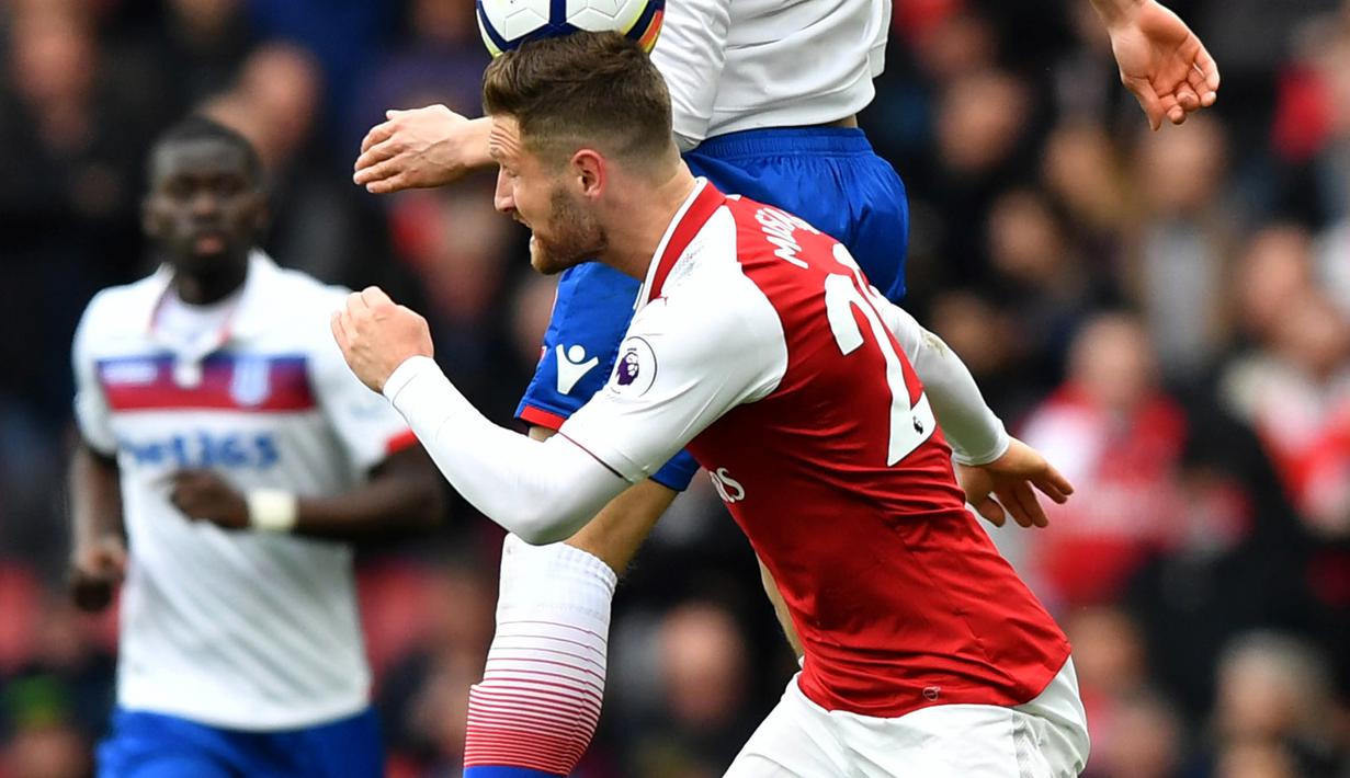 Bek Arsenal, Shkodran Mustafi, adu sundulan dengan gelandang Stoke, Ramadan Sobhi, pada laga Premier league di Stadion Emirates, London, Minggu (1/4/2018). Arsenal menang 3-0 atas Stoke. (AFP/Oliver Greenwood)