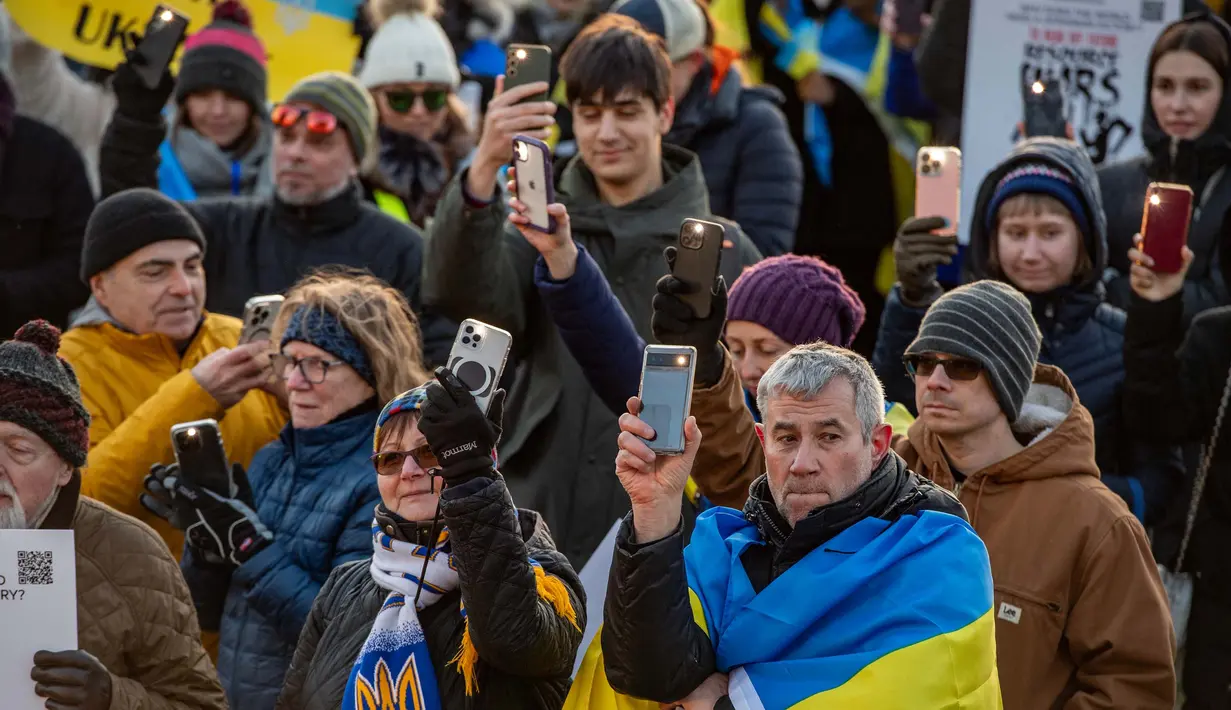 Para pendukung Ukraina memegang ponsel mereka dengan senter menyala sebagai simbol berbagi dan melindungi cahaya kebebasan dalam sebuah unjuk rasa untuk memperingati tahun kedua invasi Rusia di Boston Common, Boston, Massachusetts, 24 Februari 2024. (Joseph Prezioso/AFP)