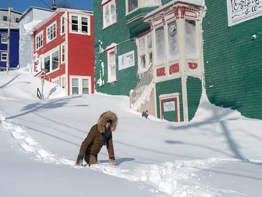 Warga berjalan melewati salju di Kota St John's, Newfoundland, Kanada, Sabtu (18/1/2020). St John's menghadapi keadaan darurat ketika salju tebal memaksa pusat-pusat bisnis tutup dan kendaraan dilarang melintas di jalan raya. (Andrew Vaughan/The Canadian Press via AP)