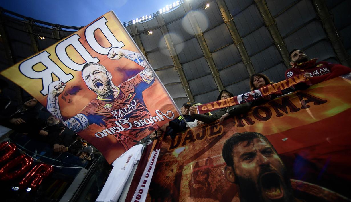 Suporter mengibarkan bendera bergambar gelandang AS Roma, Daniele De Rossi saat melawan Parma pada laga Serie A di Stadion Olympic, Roma, Minggu (26/5). Laga ini perpisahan bagi De Rossi dan AS Roma setelah 18 tahun. (AFP/Filippo Monteforte)