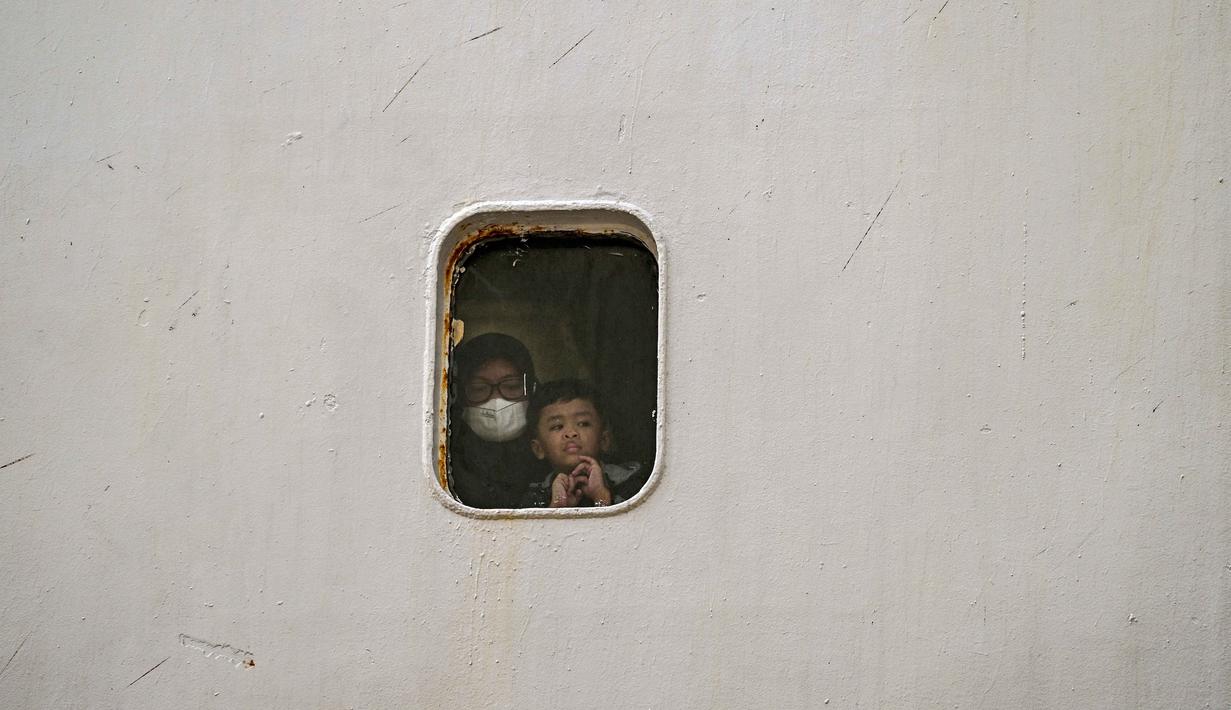 Hingga Sabtu (14/3/2026), jumlah total penumpang, baik yang berangkat maupun tiba, di Pelabuhan Tanjung Perak, Surabaya, tercatat 67.618 jiwa. Tampak dalam foto, para penumpang melihat keluar dari jendela kapal sebelum turun dari kapal di pelabuhan Perak, Surabaya, Jawa Timur pada Minggu 15 Maret 2026. (JUNI KRISWANTO/AFP)