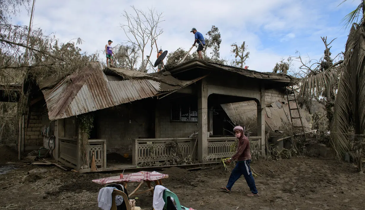 Sejumlah warga membersihkan abu vulkanik dari atap rumah mereka setelah letusan Gunung Taal di Desa Buso-Buso, Laurel, Provinsi Batangas, Filipina, Kamis (17/1/2020). Pihak berwenang Filipina memperingatkan bahwa potensi Gunung Taal untuk kembali meletus masih tinggi. (Ed JONES/AFP)