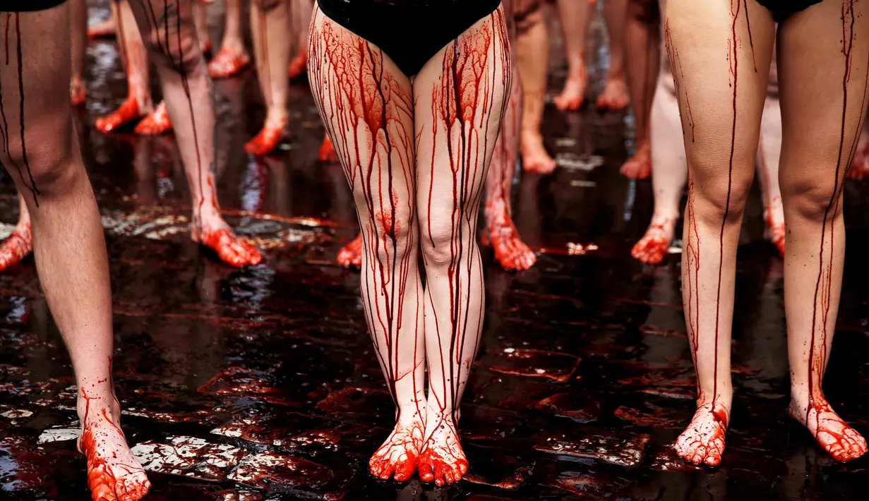 Kucuran darah palsu membasahi aktivis dalam aksi menolak festival San Fermin di Pamplona, Spanyol, (5/7). Festival yang menampilkan tradisi lari bersama banteng dan matador ini merupakan aksi yang mengorbankan hewan. (REUTERS/Susana Vera)