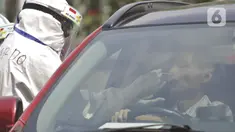 Petugas berpakaian APD lengkap melayani pasien yang secara mandiri melakukan swab test drive thru di halaman parkir rumah sakit di Jakarta, Rabu (12/5/2020). Swab test drive thru dilakukan untuk mendeteksi dan mencegah penyebaran virus corona COVID-19. (Liputan6.com/Johan Tallo)