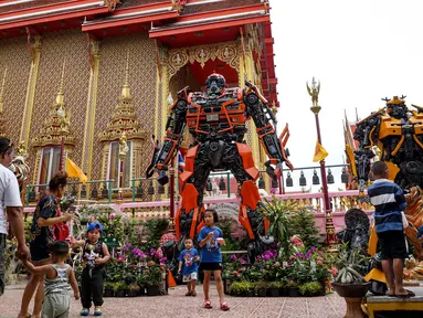 Suasana di depan kuil Buddha Wat Tha Kien yang menghadirkan patung logam raksasa yang terinspirasi oleh 'Transformers' di Nonthaburi, Thailand (18/6). Patung karya Ban Hun Lek dihadirkan untuk menarik pengunjung. (AFP Photo/Lillian Suwanrumpha)